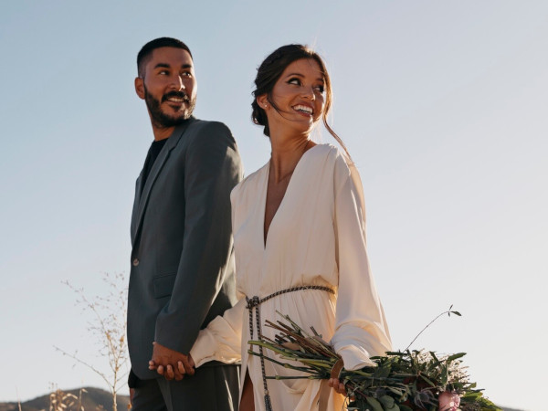 Bride and groom in a scenic field, bride holding beautiful flowers
